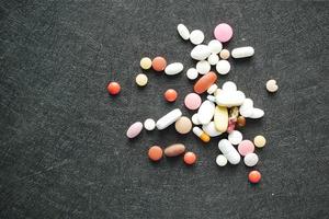 vista dall'alto di molte pillole e capsule colorate che si riversano sul nero foto