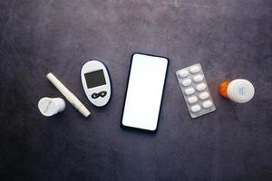 smartphone e strumenti di misurazione del diabete e pillole sul tavolo foto