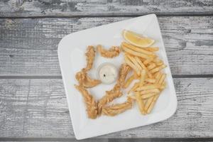 bastoncino di calamaro fritto croccante e patatine fritte sul tavolo foto