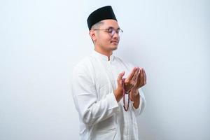 uomo musulmano asiatico che indossa abiti musulmani con in mano i grani di preghiera che pregano Dio