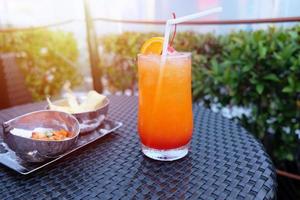 bicchiere da cocktail ghiacciato e snack sul tavolo nel bar sul tetto per la vita notturna foto