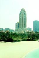 scatto verticale di un'idilliaca spiaggia sabbiosa con moderni grattacieli sullo sfondo foto