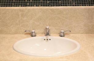 interno del bagno con lavabo e rubinetto bianchi foto