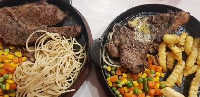 il miglior cibo del mondo bistecca di manzo insieme a patate fritte con deliziosa salsa di funghi e insalata placcata in un bellissimo piatto a strisce nere foto