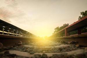 binario ferroviario su ghiaia per il trasporto in treno e tramonto leggero al mattino. foto