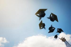 mani di laureati che lanciano cappelli di laurea. foto