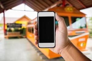 mano destra che tiene utilizzando lo smartphone con schermo nero su sfondo sfocato astratto della stazione ferroviaria. foto