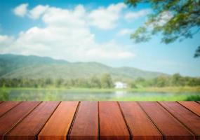 messa a fuoco selezionata tavolo in legno marrone vuoto e cielo blu o montagna sfocatura dello sfondo con immagine bokeh. per il tuo fotomontaggio o la visualizzazione del prodotto. foto