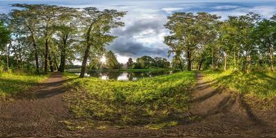 panorama hdri sferico completo senza soluzione di continuità vista angolare a 360 gradi su sentiero pedonale tra boschetto di querce vicino al lago in proiezione equirettangolare con zenit, contenuto di realtà virtuale vr ar pronto foto