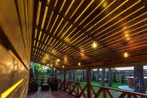 interno della veranda vuota della sala nella casa di vacanza del villaggio di legno con lampade e sedie d'epoca foto