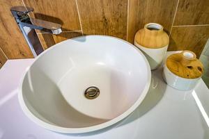 distributori di sapone e shampoo vicino al lavandino del rubinetto dell'acqua in ceramica con rubinetto nel costoso bagno a soppalco foto