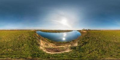 panorama hdri sferico senza soluzione di continuità vista angolare a 360 gradi sulla costa erbosa di un enorme fiume o lago in una soleggiata giornata estiva e tempo ventoso in proiezione equirettangolare con zenit e nadir, contenuto vr ar foto