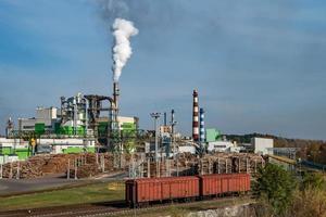 tubi della segheria dell'impianto di impresa di lavorazione del legno vicino al fiume. concetto di inquinamento atmosferico. paesaggio industriale inquinamento ambientale rifiuti di centrale termica foto