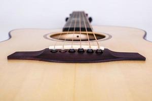 struttura in legno del ponte inferiore di una chitarra acustica a sei corde su sfondo bianco. forma di chitarra foto