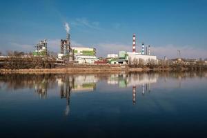 tubi della segheria dell'impianto di impresa di lavorazione del legno vicino al fiume. concetto di inquinamento atmosferico. paesaggio industriale inquinamento ambientale rifiuti di centrale termica foto