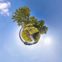 trasformazione del piccolo pianeta del panorama sferico a 360 gradi. vista aerea astratta sferica vicino al fiume con bellissime nuvole fantastiche. curvatura dello spazio. foto