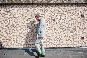 sognatore elegante uomo macho in abito grigio, cappello e occhiali in posa sul tetto. foto