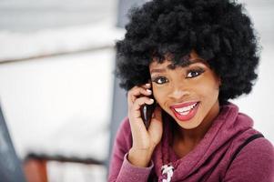 primo piano ritratto di capelli ricci donna afroamericana poste al giorno d'inverno, parlando sul telefono cellulare. foto