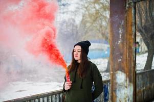 giovane ragazza con una bomba fumogena di colore rosso in mano. foto