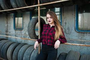 giovane ragazza hipster in camicia a scacchi nella zona di montaggio dei pneumatici. foto