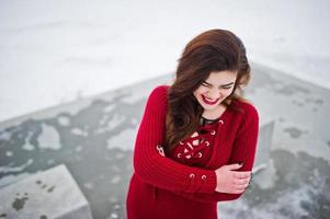 bruna modello taglie forti in rosso contro il lago ghiacciato in una giornata invernale. foto