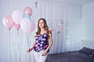 ragazza felice con palloncini colorati sul letto in camera. festeggiare il tema del compleanno. foto