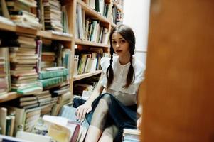 ragazza con le trecce in camicetta bianca alla vecchia biblioteca. foto