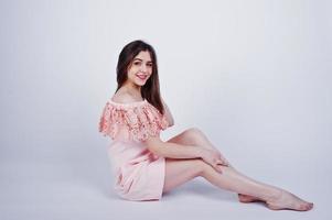 ritratto di una donna alla moda in abito rosa seduta e in posa sul pavimento in studio. foto