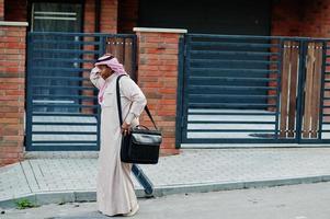 uomo d'affari arabo mediorientale posato su strada contro un edificio moderno con borsetta nera. foto