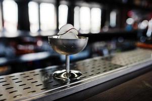 cocktail alcolico con ghiaccio e cocco in vetro argentato sul tavolo da bar. foto