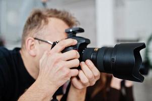 primo piano fotografo al lavoro con grande fotocamera e obiettivo. riprese professionali. foto