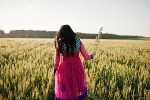 tenera ragazza indiana in saree, con labbra viola compongono poste in campo al tramonto. modello indiano alla moda. foto