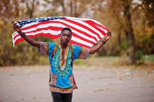 uomo africano in africa camicia tradizionale sul parco autunnale con bandiera usa. foto