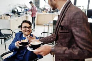 due uomini d'affari indiani in giacca e cravatta seduti in ufficio al bar e bere caffè. foto