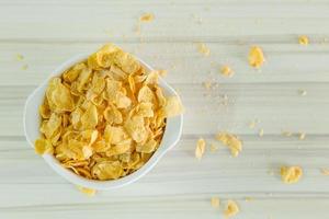 immagine primo piano cereali cornflakes colazione in una ciotola bianca sul tavolo di legno. foto