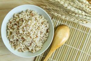 riso integrale in ciotola bianca su tavola di legno per contenuto alimentare salutare. foto