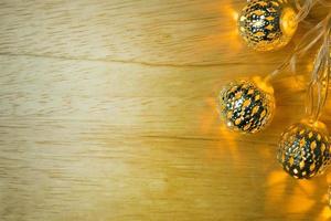 decorazioni natalizie con palla di luci dorate su tavola di legno. foto