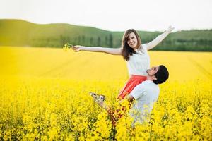 il ritratto di una giovane coppia di famiglia felice sente felicità e libertà, posa insieme sul prato giallo contro il cielo blu, dimostra positività e vera relazione. giovani romantici all'aperto foto