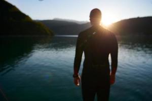 atleta di triathlon che inizia l'allenamento di nuoto sul lago foto