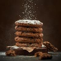 i biscotti rotondi al cioccolato sono cosparsi di zucchero a velo su uno sfondo marrone. foto