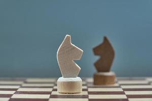 un cavaliere bianco di scacchi contro un cavaliere nero in una sfocatura. foto