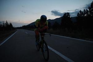 atleta di triathlon in bicicletta di notte foto