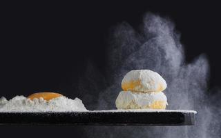 la farina si versa sulla pasta fresca fatta in casa. impasto con farina versata su sfondo nero. pasta lievitata per pane, panini, pizza o torta. copia spazio. foto