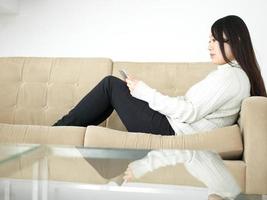donna asiatica con tavoletta digitale sul divano foto
