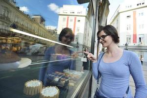 donna davanti alla vetrina del negozio di dolci foto