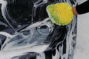 concetto di lavoro manuale umano. l'uomo lava l'auto con sapone e panno. pulizia del veicolo. Immagine ravvicinata di un'automobile per il lavaggio del mocio a mano foto