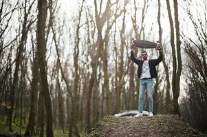 street style uomo arabo in occhiali da vista con longboard su legno. foto