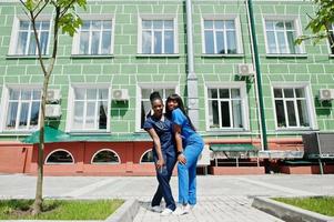 due giovani belle ragazze afroamericane medico in cappotto con uno stetoscopio contro l'ospedale. foto