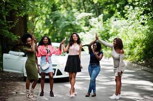 gruppo di cinque afroamericani felici che camminano contro l'auto bianca. foto
