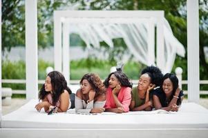 gruppo di cinque ragazze afroamericane che si rilassano nella bellissima cabana a bordo piscina accanto al resort di lusso. foto